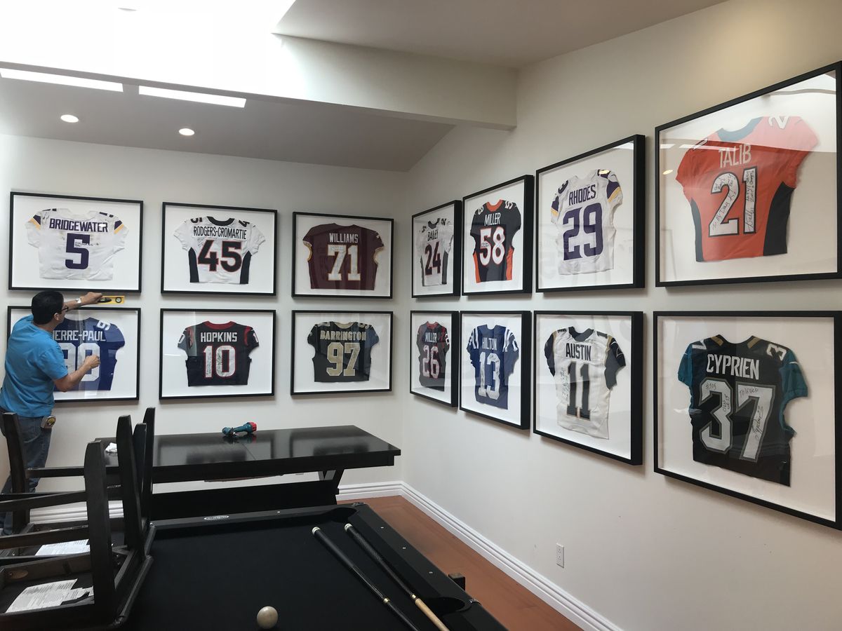 Wall of signed football jerseys in custom shadow box frames