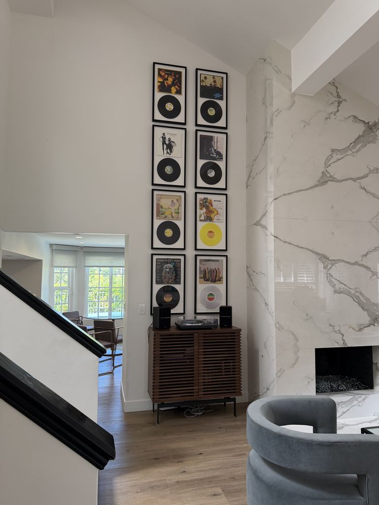 Vertical gallery wall of framed vinyl records and album covers in matching black frames