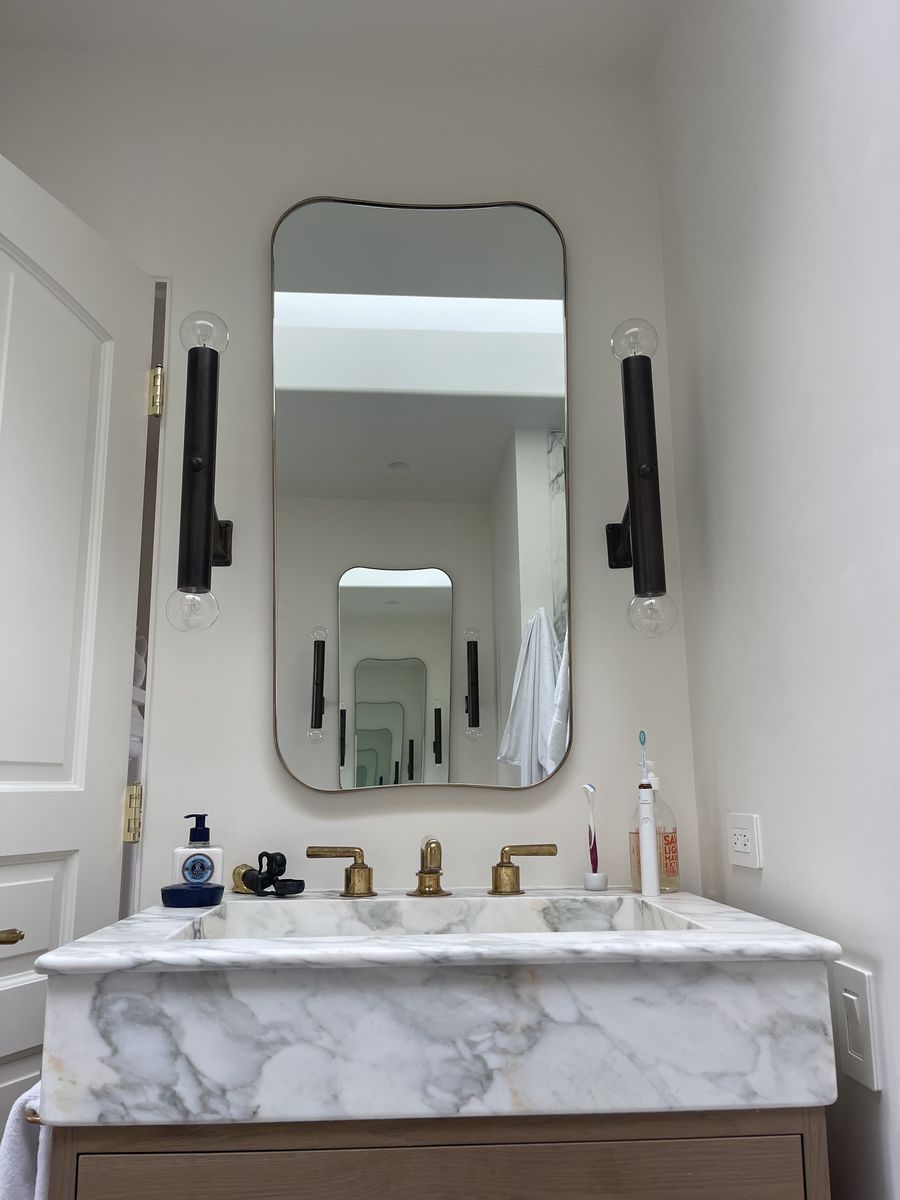 Brass-framed mirror above a marble vanity